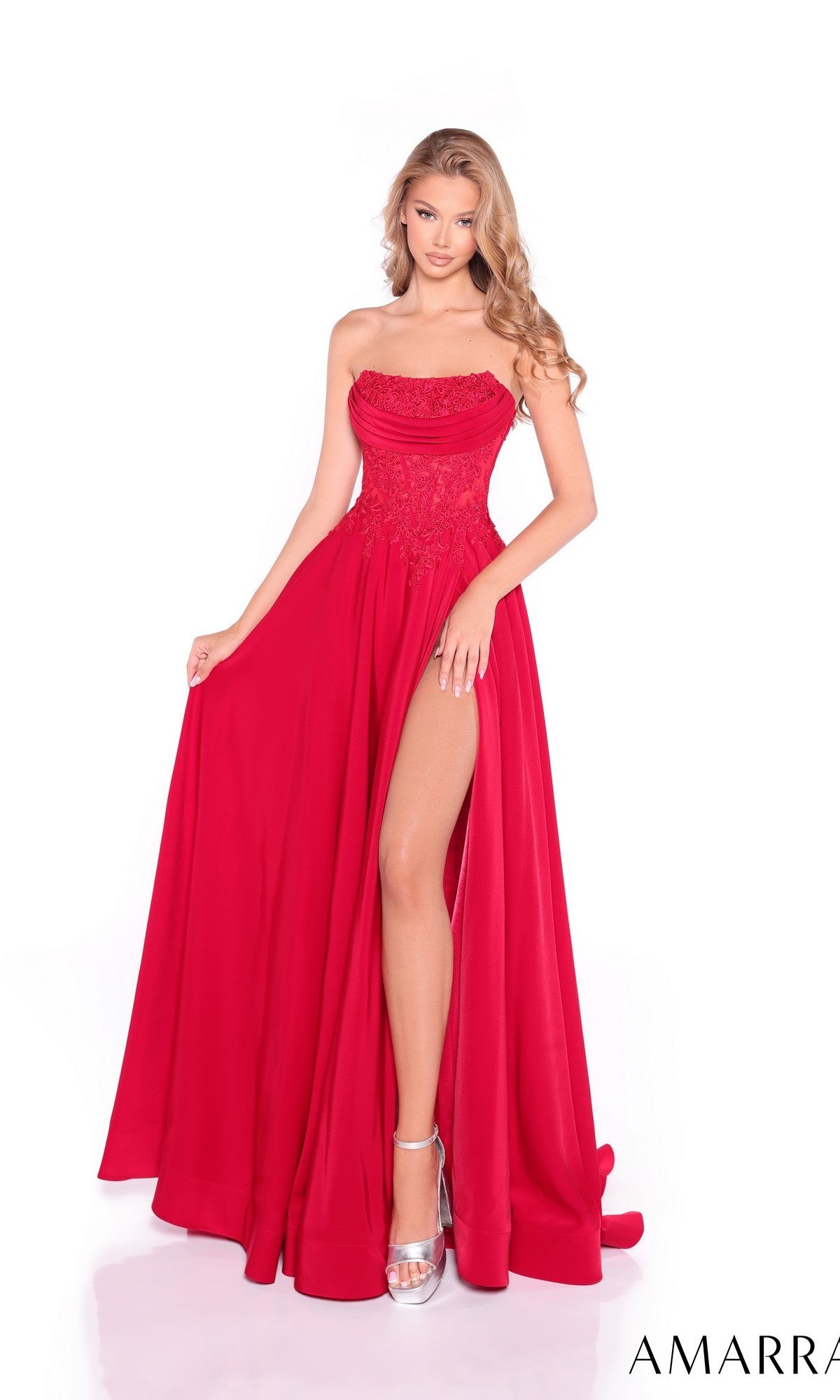 A woman models the Amarra 89421 long prom dress—a bright red, strapless ball gown featuring a lace corset bodice and a high leg slit—posed against a white background.